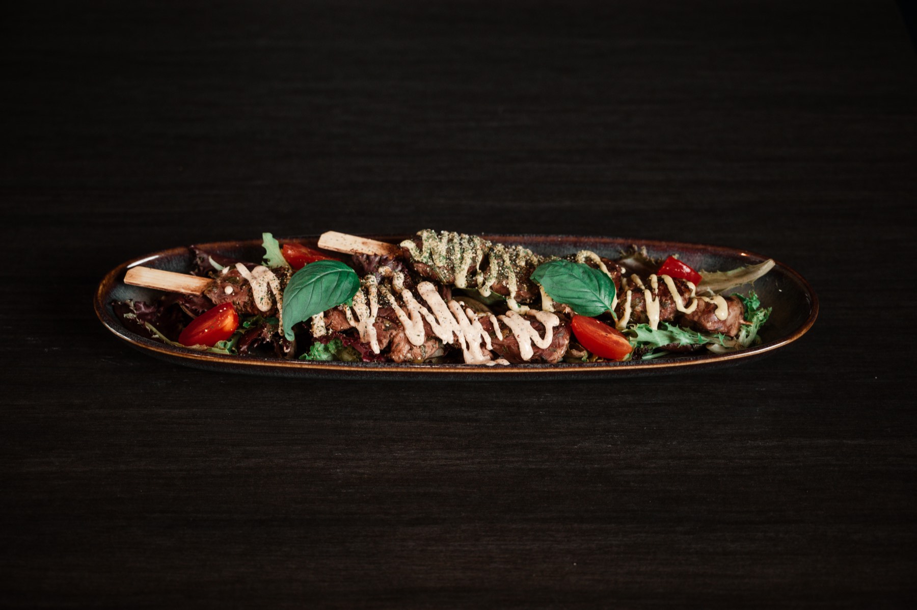 Brochettes de viande dressées sur une assiette longue